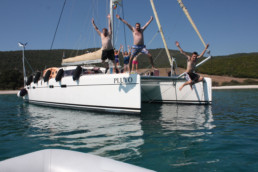 Happy charter clients jumping from pluto catamaran