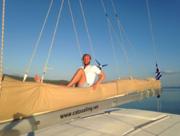 A happy charter client on the boom of Pluto catamaran